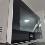 Horno microondas Kalley de diseño moderno, con panel de control táctil y acabado reflectante, colocado sobre una superficie.
