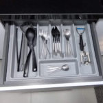 Cajón de cocina con organizador de cubiertos que incluye cucharas, tenedores, cuchillos, utensilios de cocina, un pelador y un sacacorchos.