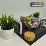 Mesa de comedor con una canasta de snacks, servilletero, portavasos de madera y plantas decorativas.