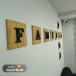 Decoración en la pared con letras en relieve sobre madera formando las palabras "FAMILIA" y "VIDA", junto a una cámara de seguridad en la esquina.